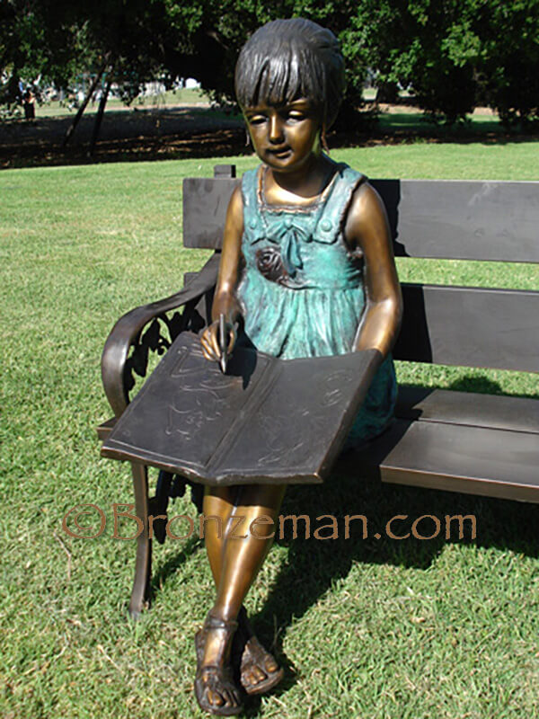 bronze statue of girl and cat on a bench