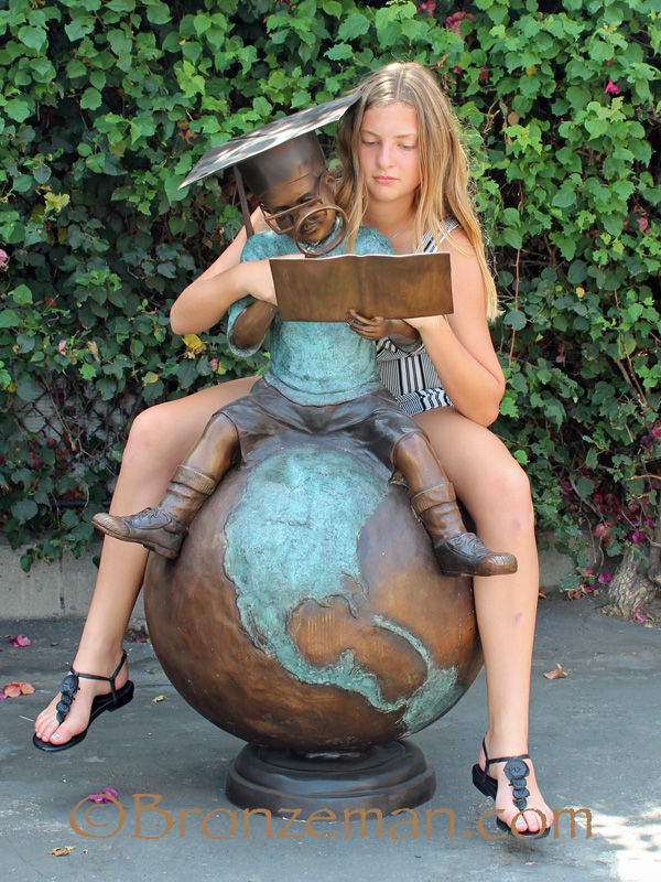 bronze statue of boy reading on globe