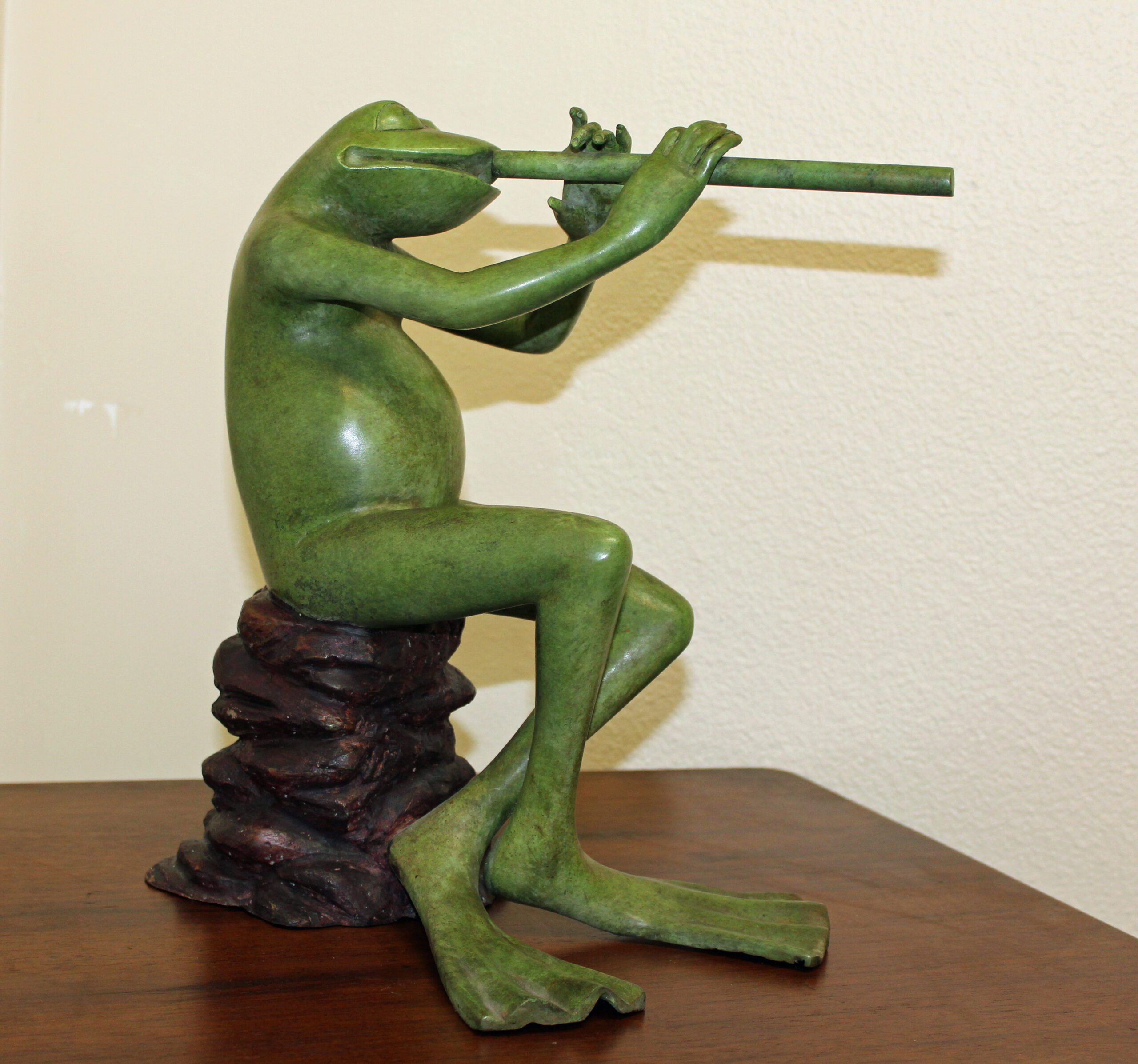 bronze statue of frog playing flute