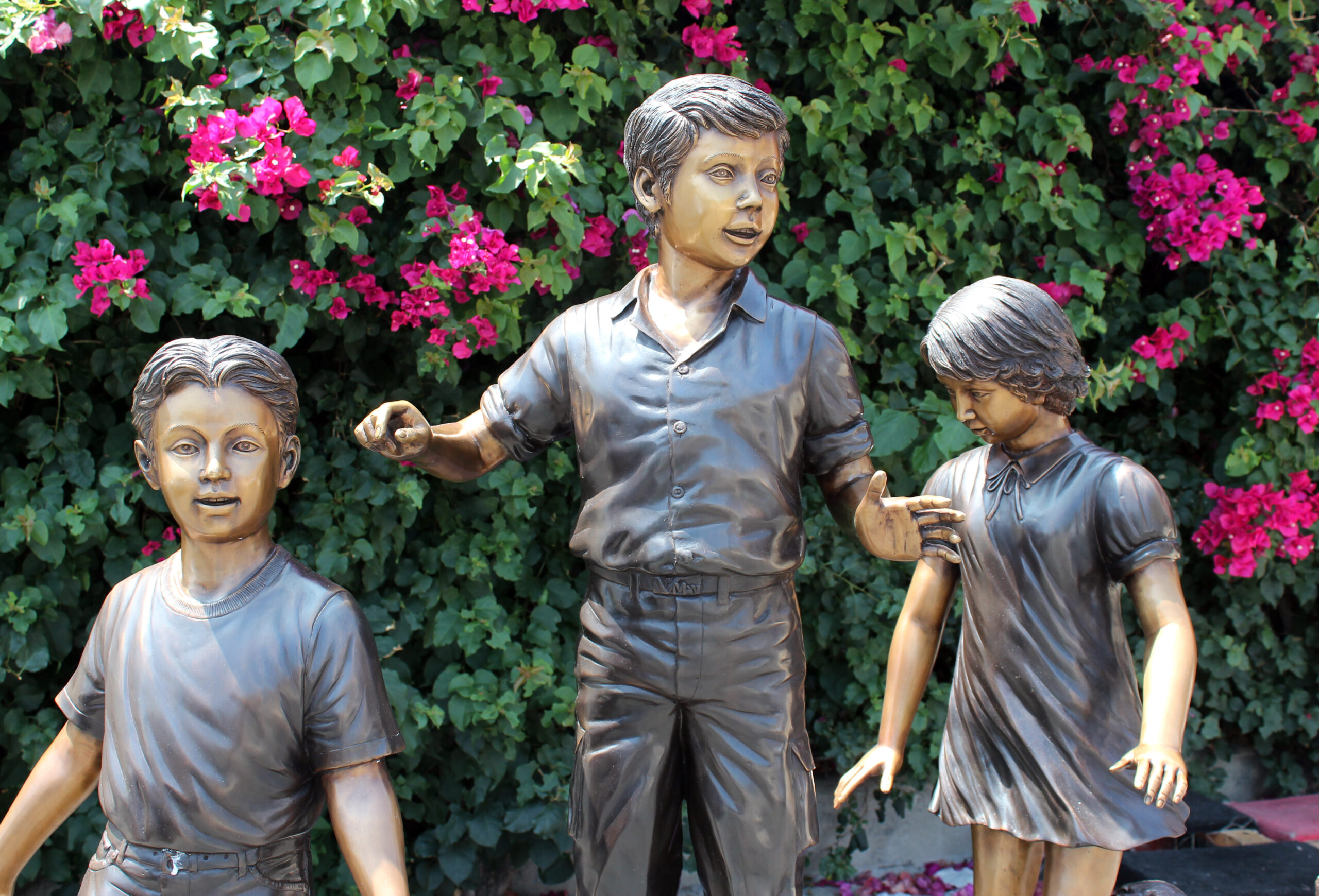 bronze statue of children on log
