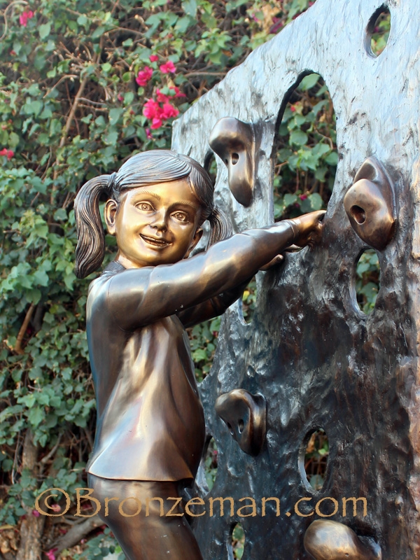 bronze statue of a girl rock climbing