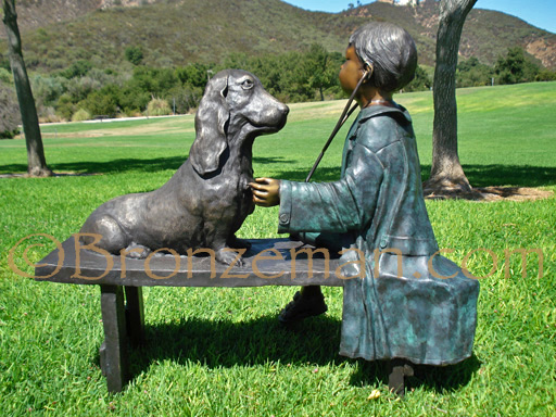 bronze statue of a girl on bench with dog