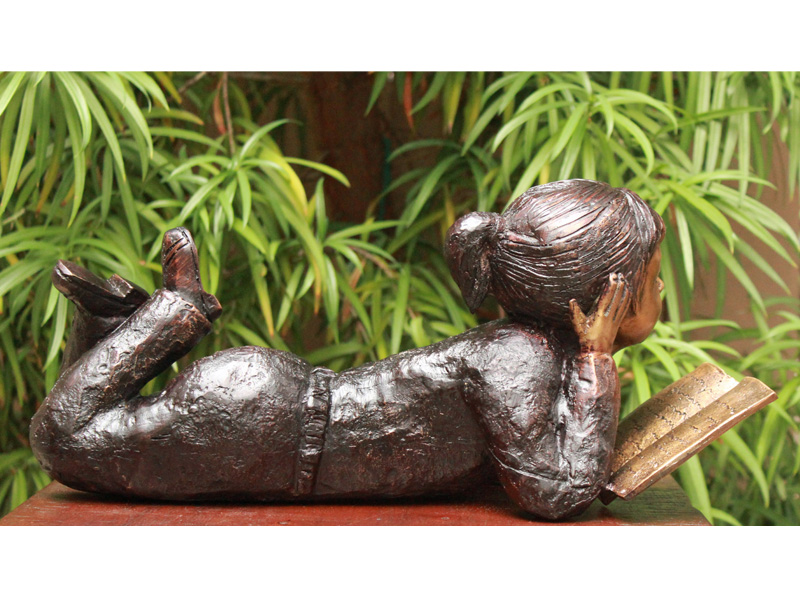 bronze statue of a girl reading book