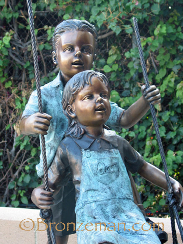 bronze statue of children on a swing