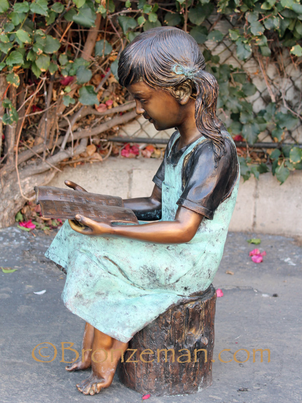bronze statue of a girl reading a book