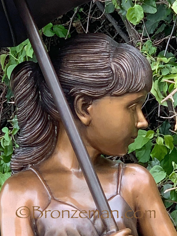 bronze statue of girl with umbrella