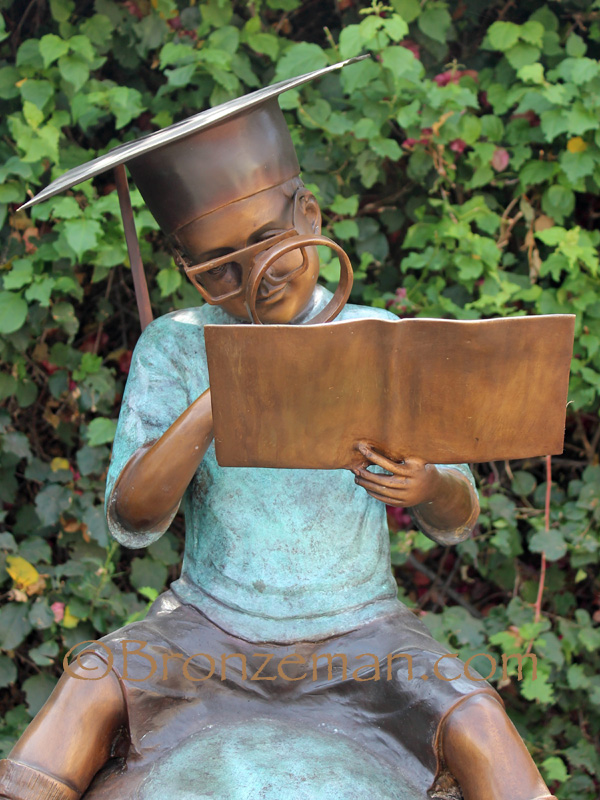 bronze statue of boy reading on globe