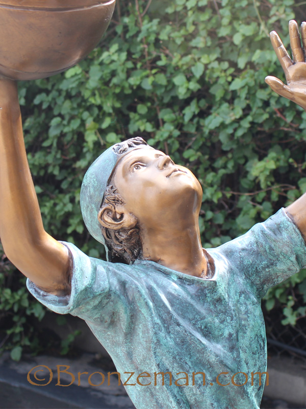 bronze statue of a boy playing basketball