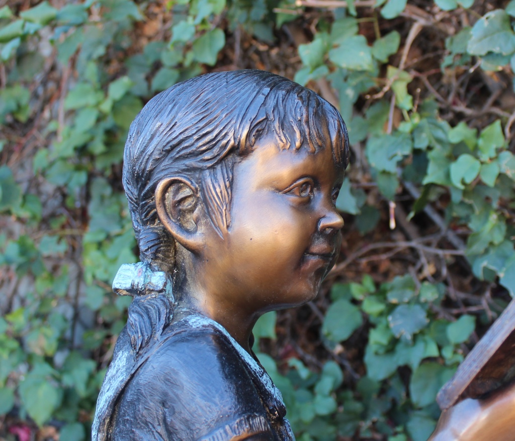 bronze statue of young girl reading