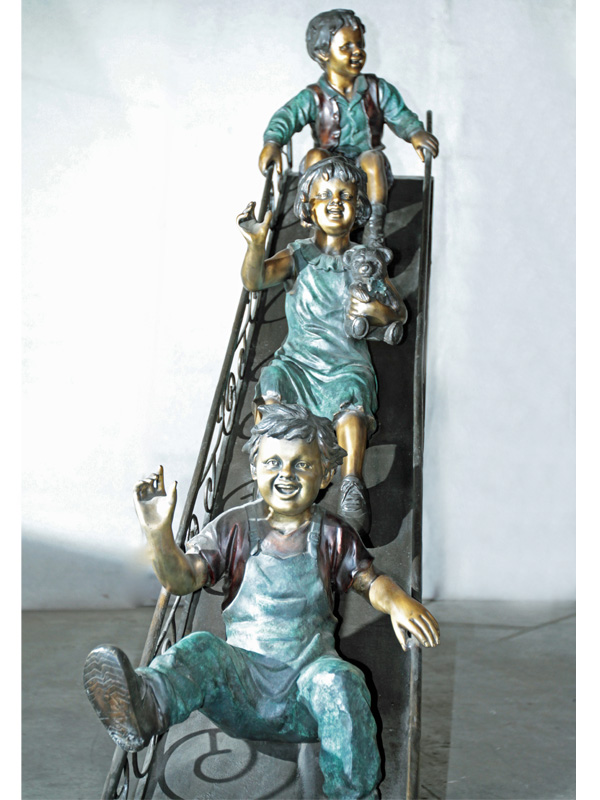 bronze statue of children playing on a slide