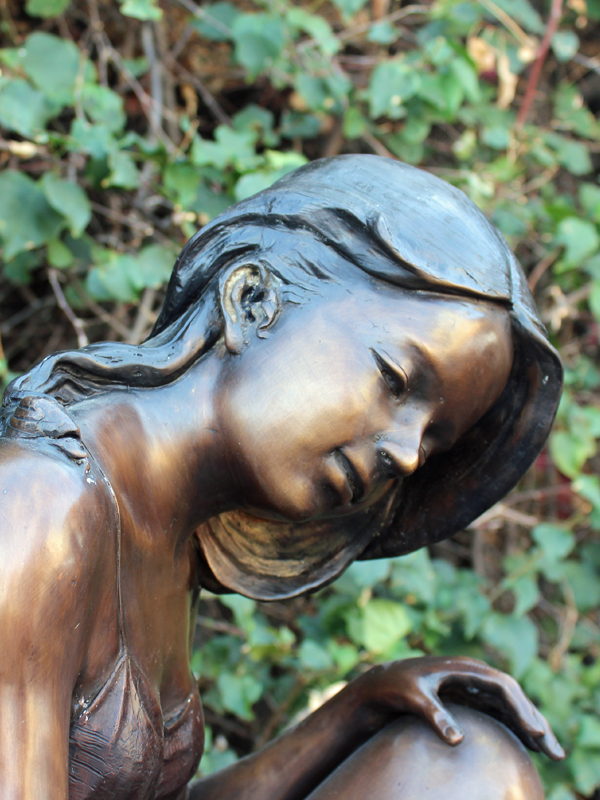 bronze statue of a girl sitting on a leaf