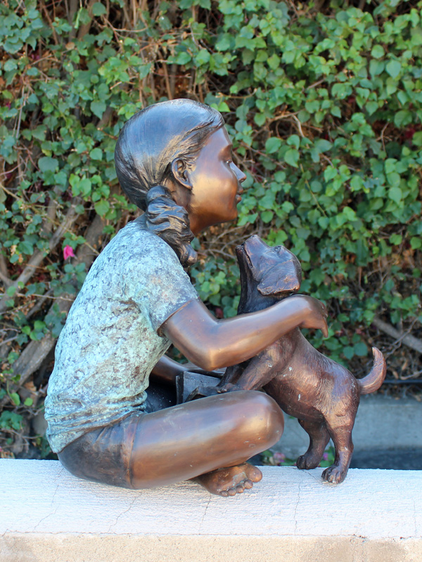 bronze statue of girl petting dog