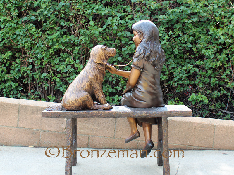 bronze statue of girl with dog on bench