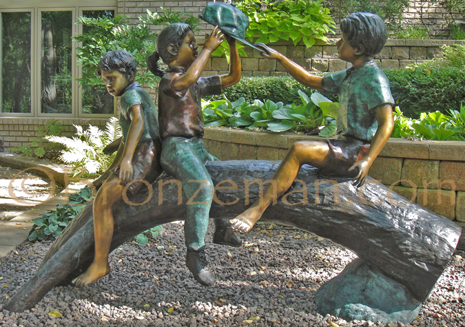 bronze statue of children on log
