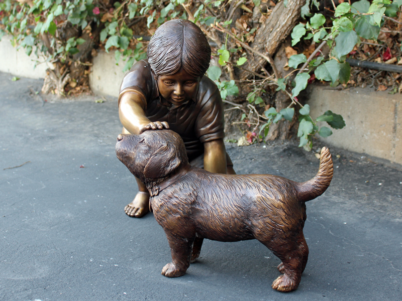 bronze statue of boy petting dog
