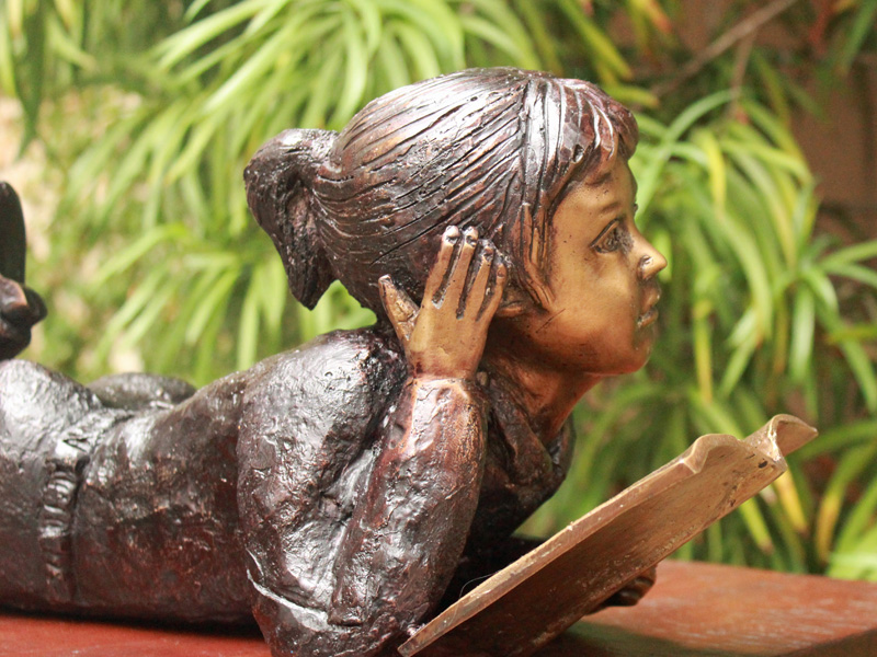 bronze statue of a girl reading book