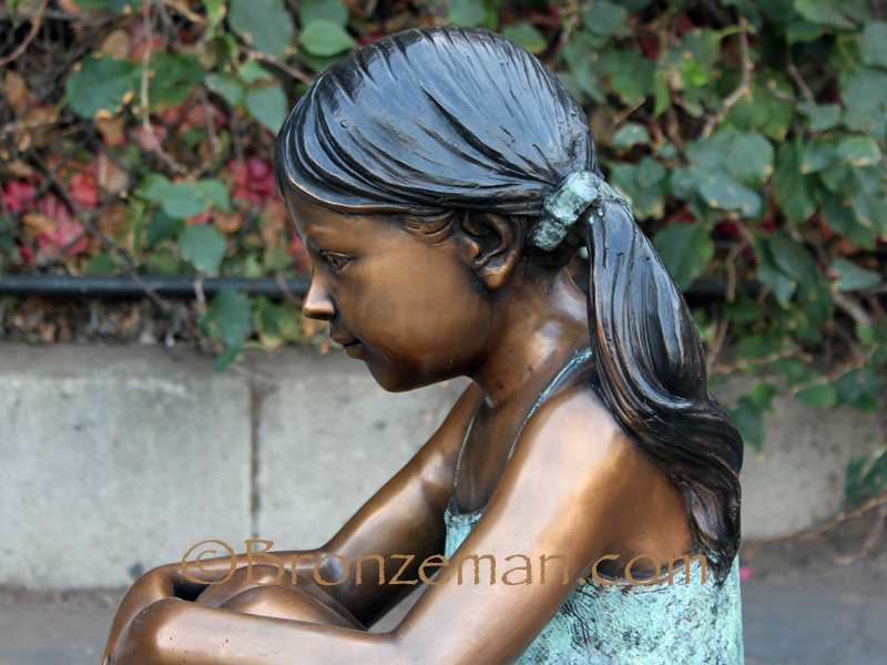 bronze statue of a girl sitting
