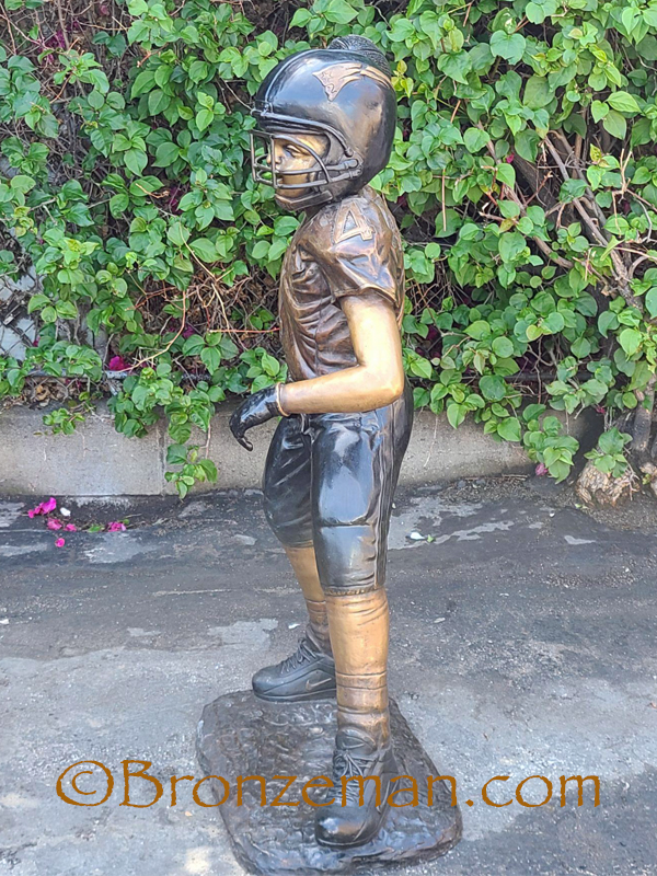 bronze statue of a boy playing football