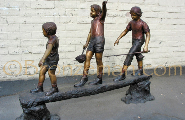 bronze statue of children playing on a log