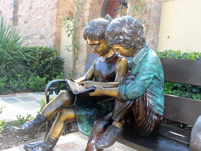 bronze statue of kids reading on bench
