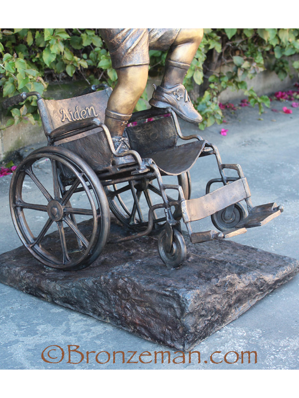 custom bronze statue of a boy climbing out of a wheelchair