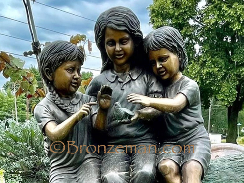 bronze statue of children playing with bird