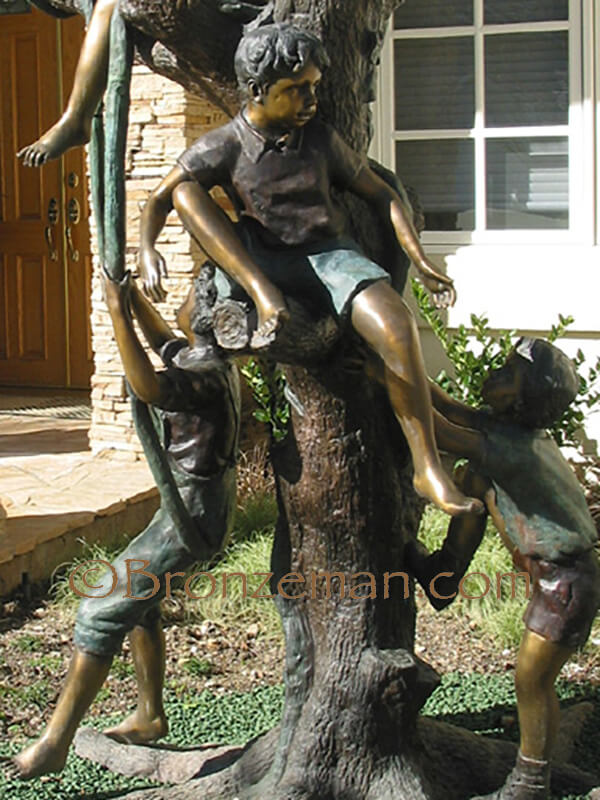 bronze statue of children playing in a tree