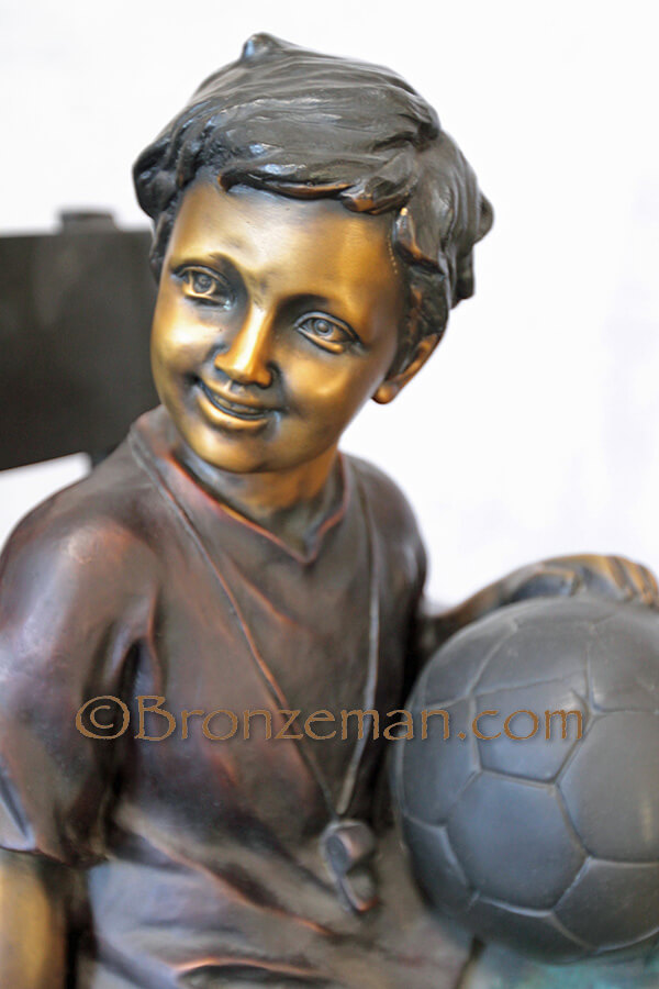 bbronze statue of boy on bench with soccer ball