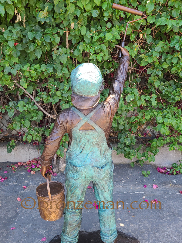 bronze statue of a boy painting