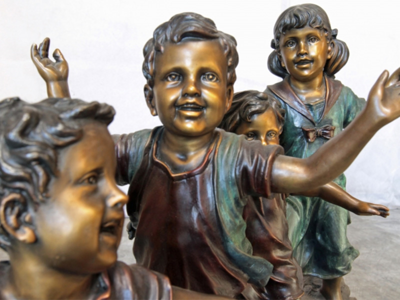 bronze statue of children playing on a log