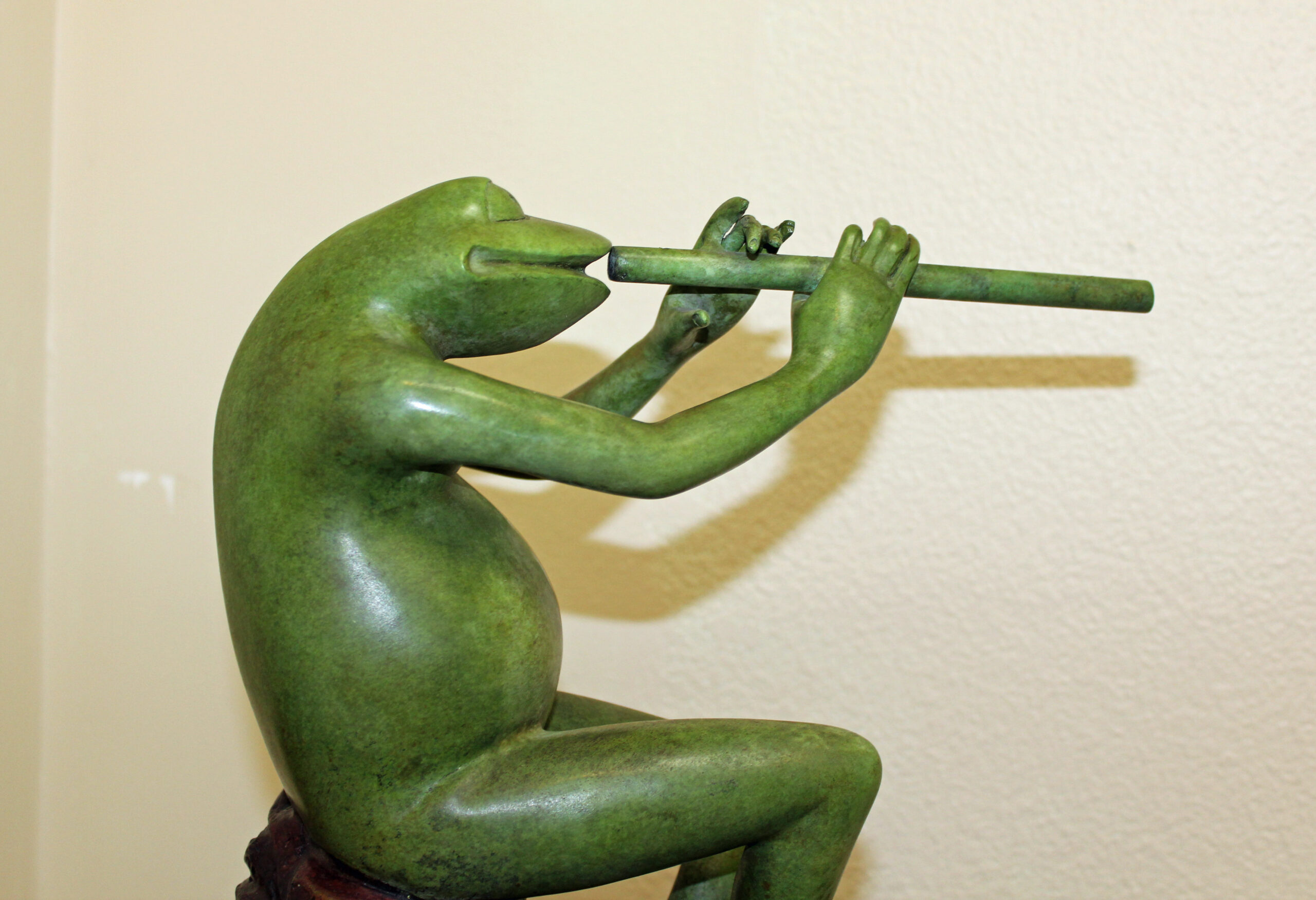 bronze statue of frog playing flute