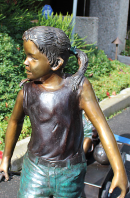 bronze statue of girl pulling a boy in a wagon