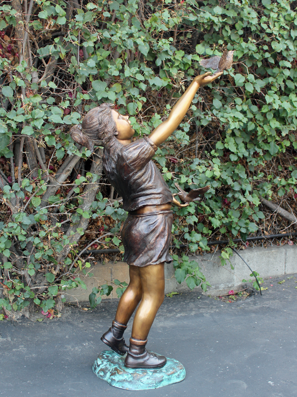 bronze statue of a girl releasing a bird