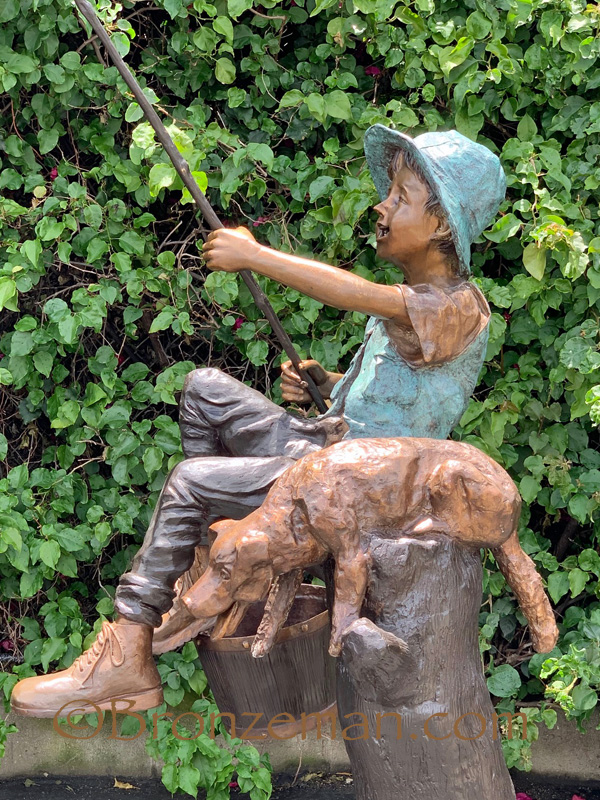 bronze statue of boy fishing with dog