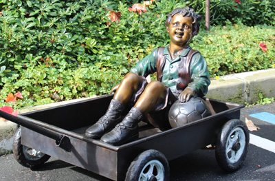 bronze statue of girl pulling a boy in a wagon