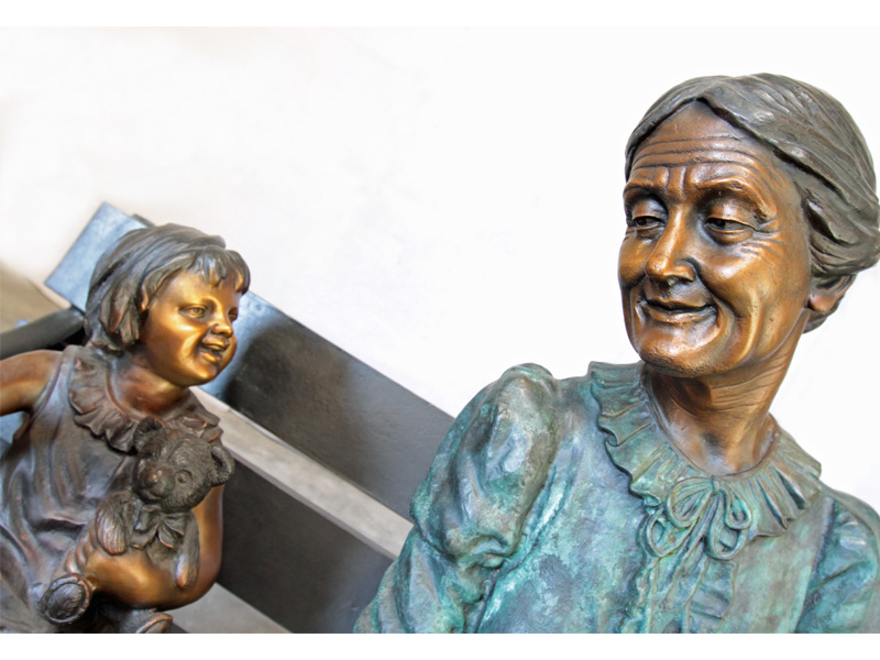 bronze statue of grandmother and girl on bench