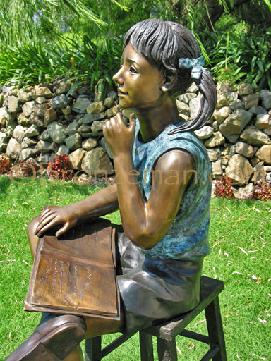 bronze statue of girl with book