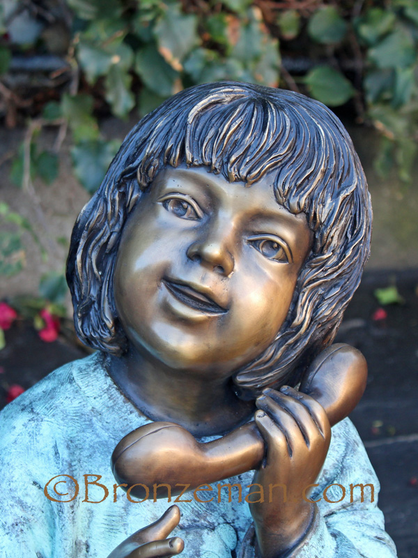bronze statue of a girl talking on the phone