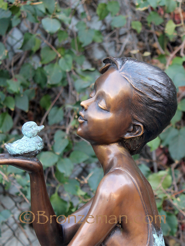 bronze sculpture of a girl with bird