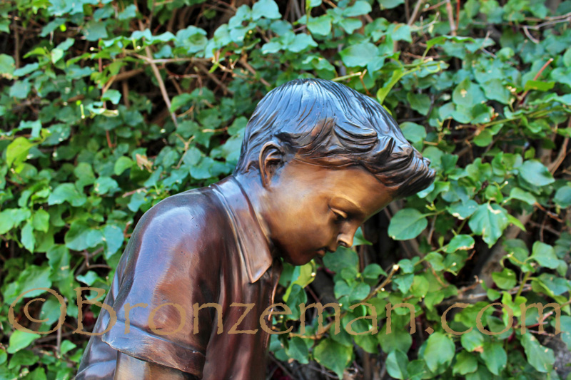 bronze statue of a boy golfing