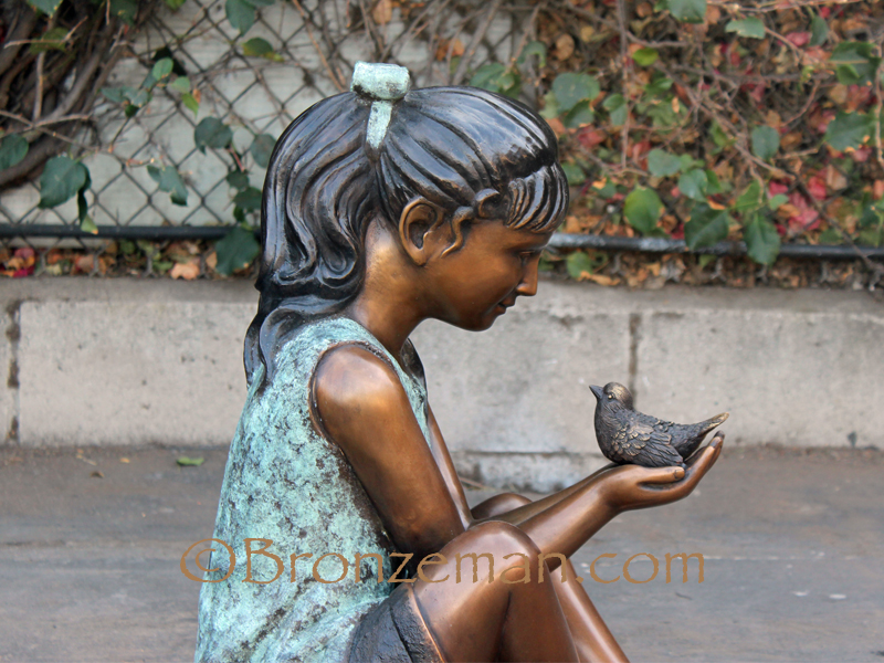 bronze statue of a girl and bird