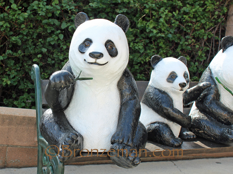 bronze statue of pandas on bench