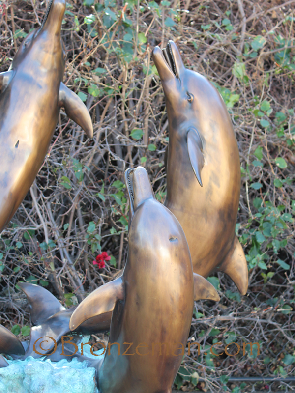 4 bronze dolphins dancing in waves