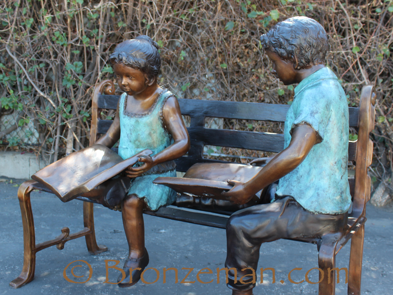bronze statue of children reading on bench